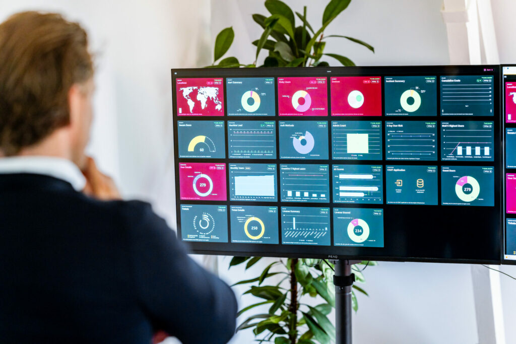 IT professional analyseert dashboards met bedrijfsdata voor cloudoptimalisatie. Essentieel voor Business IT alignment in moderne IT bedrijven.